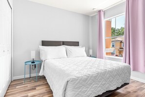 Une chambre à coucher avec un lit, des tables de chevet, une fenêtre avec des rideaux et une vue sur l’extérieur.