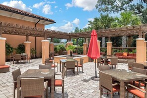 An outdoor patio area with wicker furniture, a red umbrella, and a water feature. - 4BR Family Escape | Waterslides | Near Disney (Kissimmee)