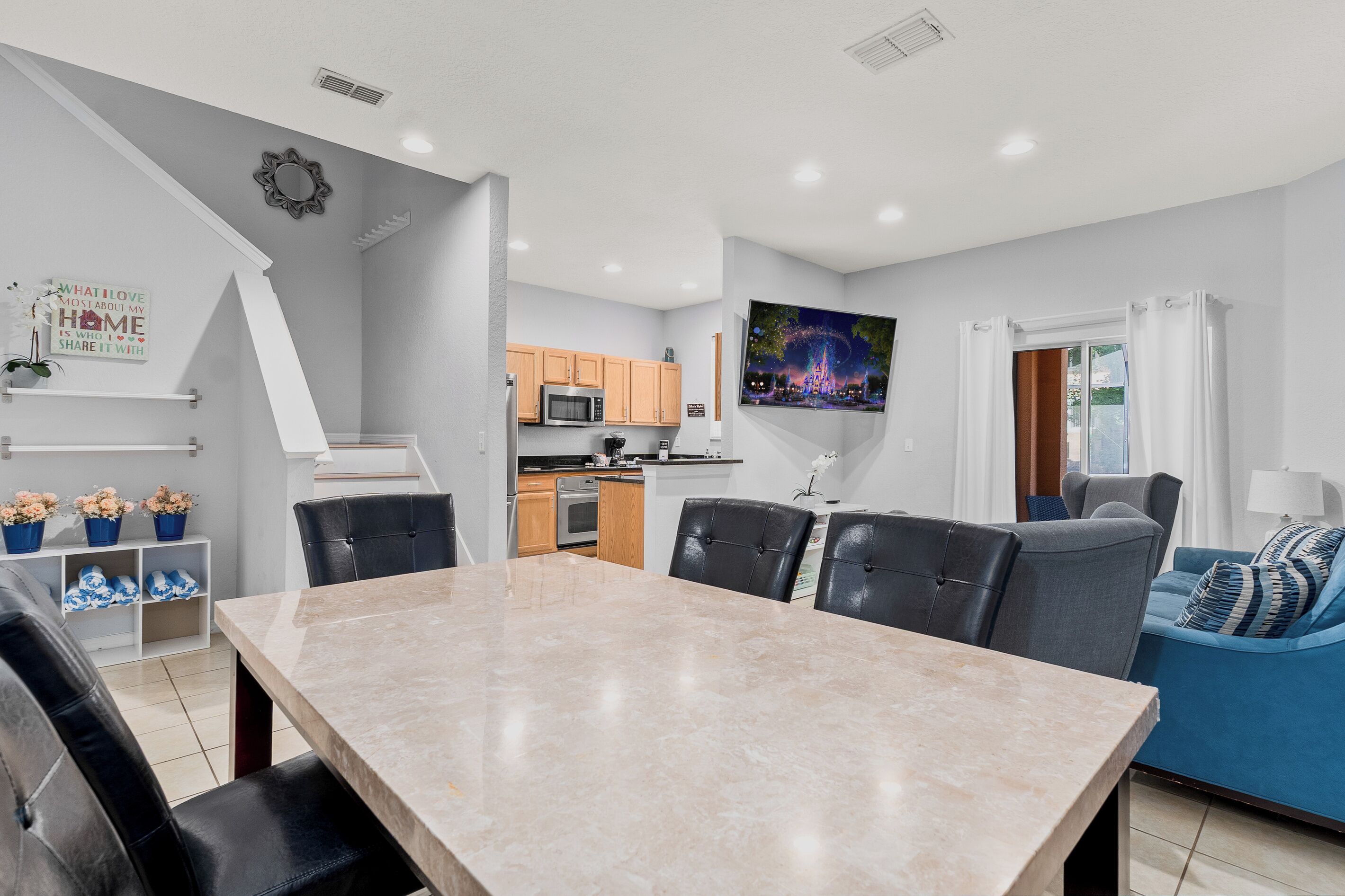 Una cocina moderna con comedor, un televisor montado en la pared y una zona de estar acogedora con sofá y sillones.