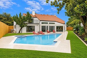 A modern house with a swimming pool, red lounge chairs, and a well-maintained lawn. - Beautifully Renovated High ceiling spacious 5-bedroom house in Houston with pool (Houston)