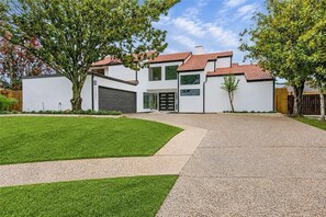 A modern two-story house with a garage, a well-maintained lawn, and a paved driveway. - Beautifully Renovated High ceiling spacious 5-bedroom house in Houston with pool (Houston)
