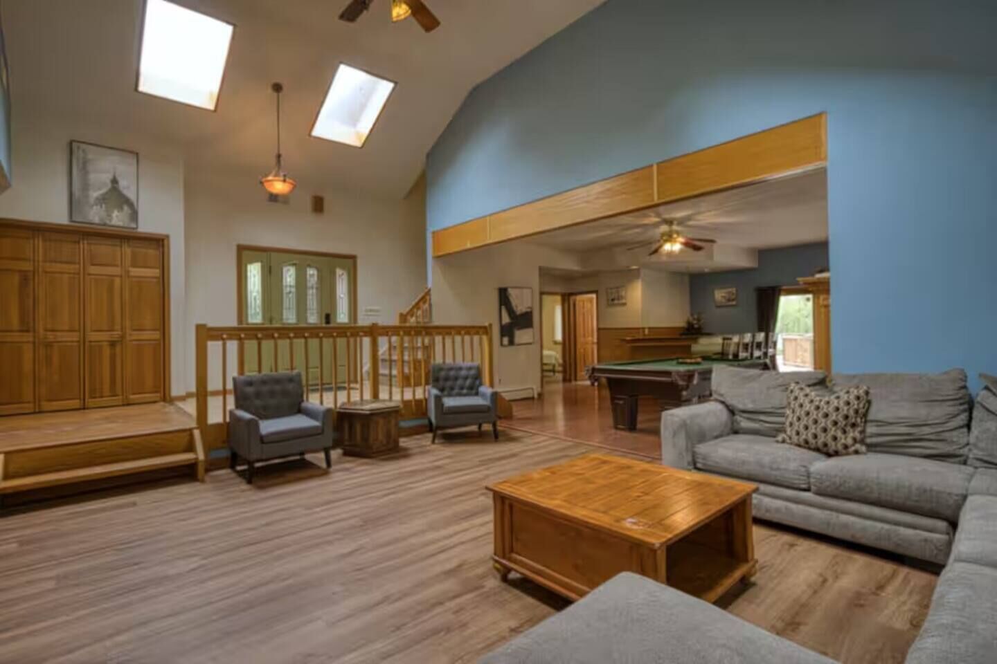 A spacious living area with a pool table, sofas, and a wooden coffee table.