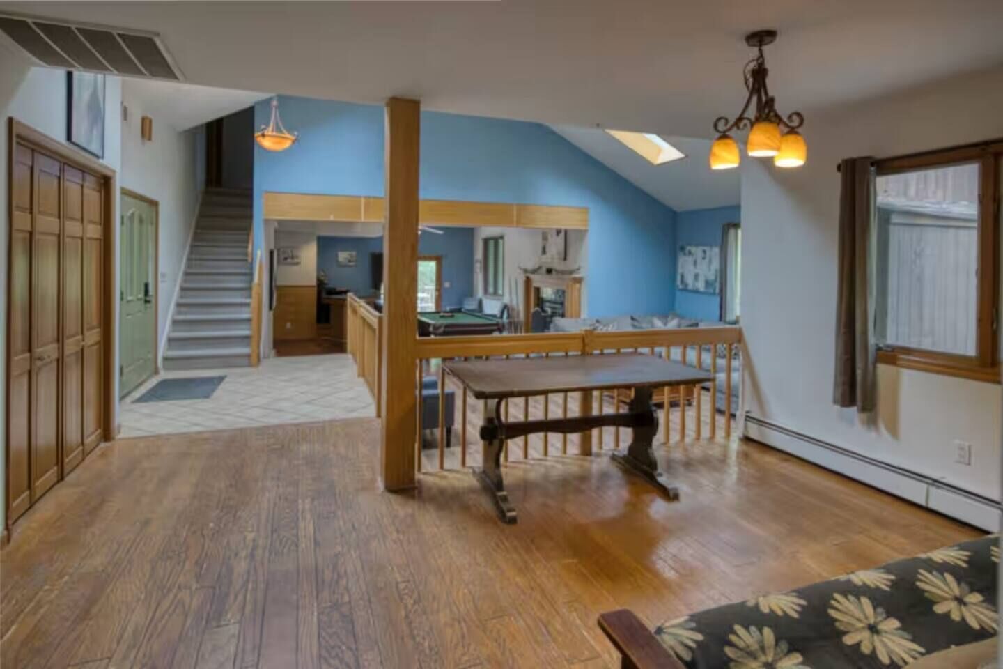Um quarto amplo com piso de madeira, uma mesa de jantar e um sofá.