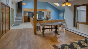 A spacious room with a wooden floor, a dining table, and a sofa. - Secluded 6BR Retreat Near Lake Hopatcong (Roxbury Township)