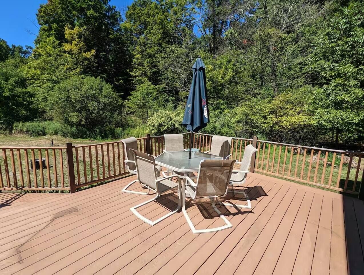 A wooden deck with a table and chairs, surrounded by a wooden railing.