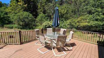 A wooden deck with a table and chairs, surrounded by a wooden railing.