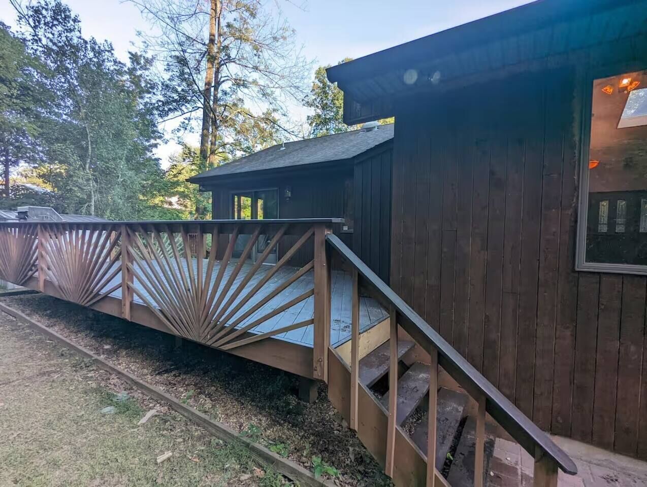 A wooden cabin with a wooden staircase leading to a deck.