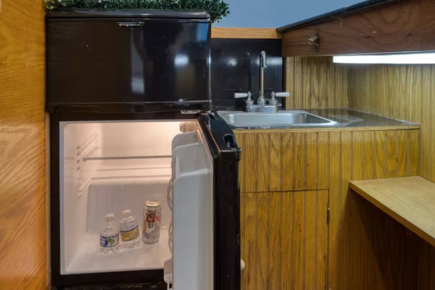 Eine kompakte Küche mit Einbaukühlschrank, Spüle und Holzschränken.