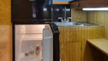 Eine kompakte Küche mit Einbaukühlschrank, Spüle und Holzschränken.