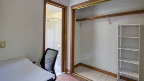 A room with a white table, a black office chair, a wooden closet with shelves, and a door leading to another room. - Secluded 6BR Retreat Near Lake Hopatcong (Roxbury Township)