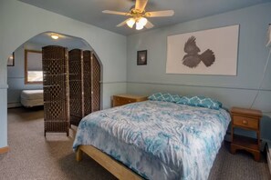 A bedroom with a bed, a nightstand, a ceiling fan, a wall-mounted artwork, and a window with blinds. - Secluded 6BR Retreat Near Lake Hopatcong (Roxbury Township)