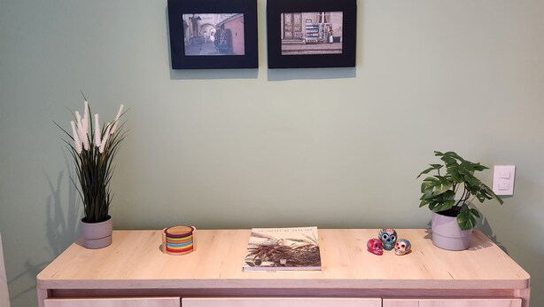 A wooden desk with two framed photographs, a potted plant, a book, and decorative skulls. - Cozy and sophisticated apartment with a pool, gym, and spa in the Financial District (Bogotá)