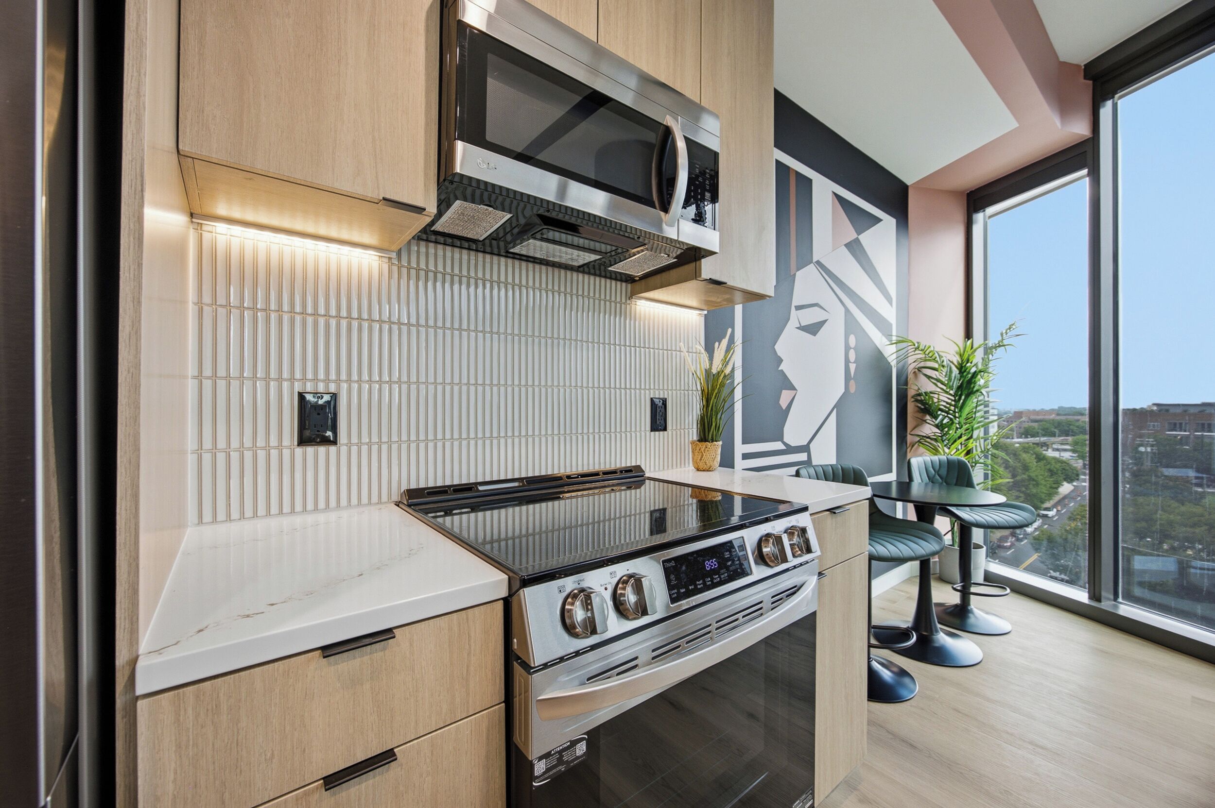 A modern kitchen with a built-in oven, microwave, and a large window offering a city view.