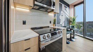 A modern kitchen with a built-in oven, microwave, and a large window offering a city view.