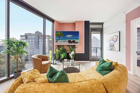 A modern living room with a large window, a sofa, a chair, and a coffee table.