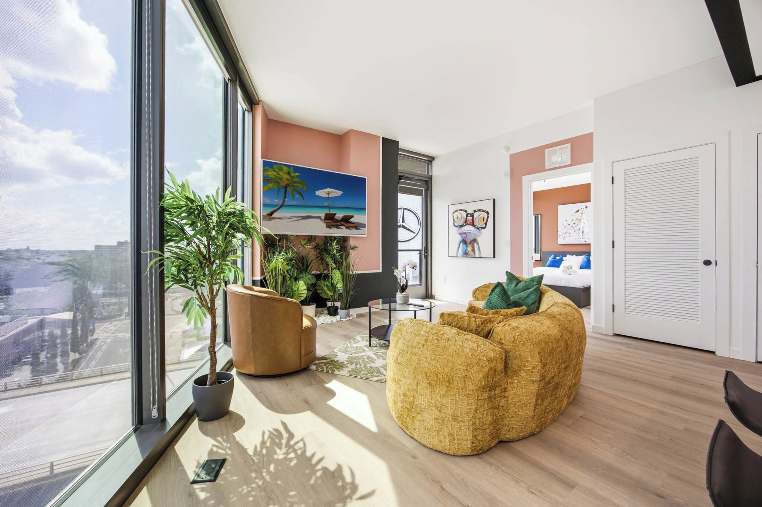 A modern living room with a large window, a sofa, a coffee table, and a plant.