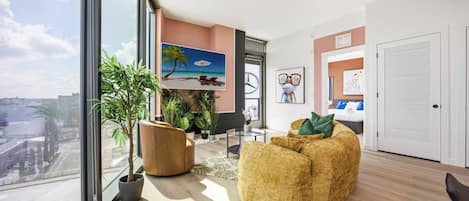 Un salon moderne avec une grande fenêtre, un canapé, une table basse et une plante.