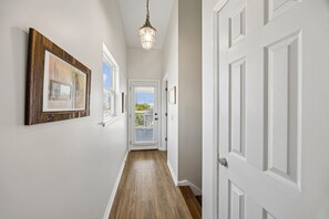 A hallway with a wooden floor, white walls, and a door with a keyhole. - 3BR/3BA Multilevel Condo | Steps to Pool & Beach | Monthly Stays (Fernandina Beach)