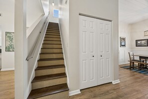 A staircase with a wooden finish and a white door with panels. - 3BR/3BA Multilevel Condo | Steps to Pool & Beach | Monthly Stays (Fernandina Beach)