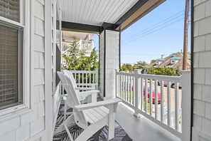 A covered porch with white railings and two white Adirondack chairs. - North End 5BR/ 2.5BA Unit 2 - Walk to Beach & Boardwalk (Ocean City)