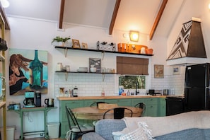 A cozy kitchen with a dining area, featuring a coffee maker, a kettle, and a painting on the wall. - The Perky Turkey in Sherwood Forest (Brevard)