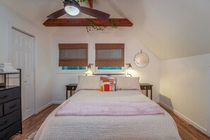 A bedroom with a bed, two bedside tables, a ceiling fan, and a window with a view. - The Perky Turkey in Sherwood Forest (Brevard)