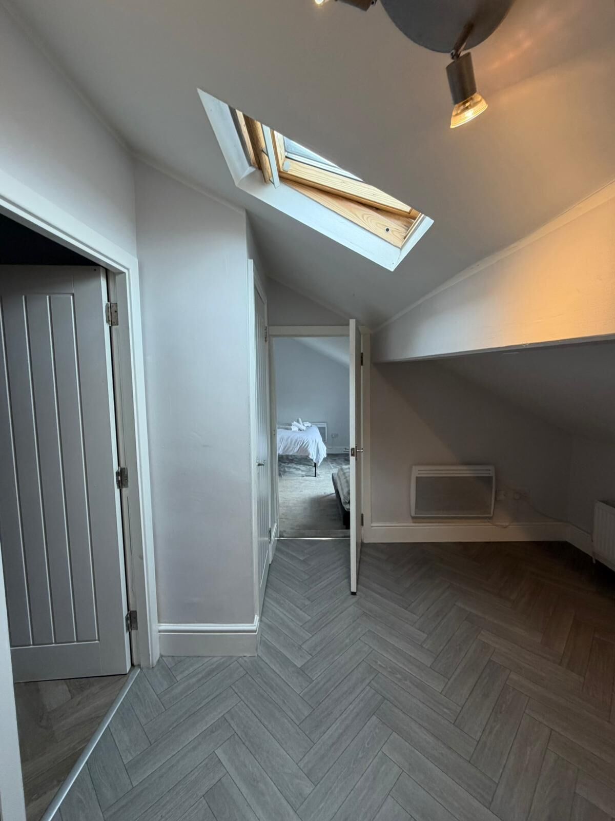 A room with a sloped ceiling, a skylight, and a herringbone-patterned floor.
