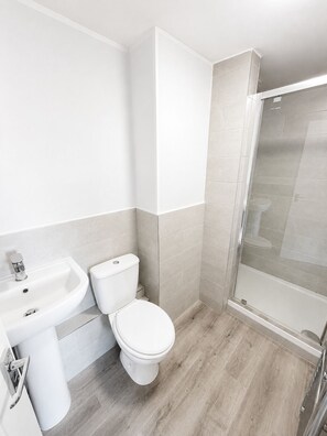 Un baño moderno con inodoro, lavamanos y ducha.