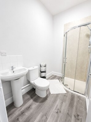 Ein Badezimmer mit weißem Waschbecken, WC und Dusche.