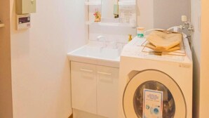 A compact bathroom with a washing machine, a sink, and a mirror.