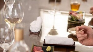 A dining table with wine glasses, a bottle, and a plate of food.