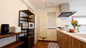 A compact kitchen with a built-in microwave, a coffee maker, and a shelf unit.