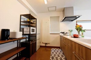 A compact kitchen with a built-in microwave, a coffee maker, and a shelf unit.