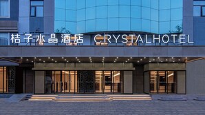 Ein Hotel Eingang mit Glasfassade, Beschilderung mit 'CRYSTAL HOTEL' und einem gut beleuchteten Eingangsbereich.