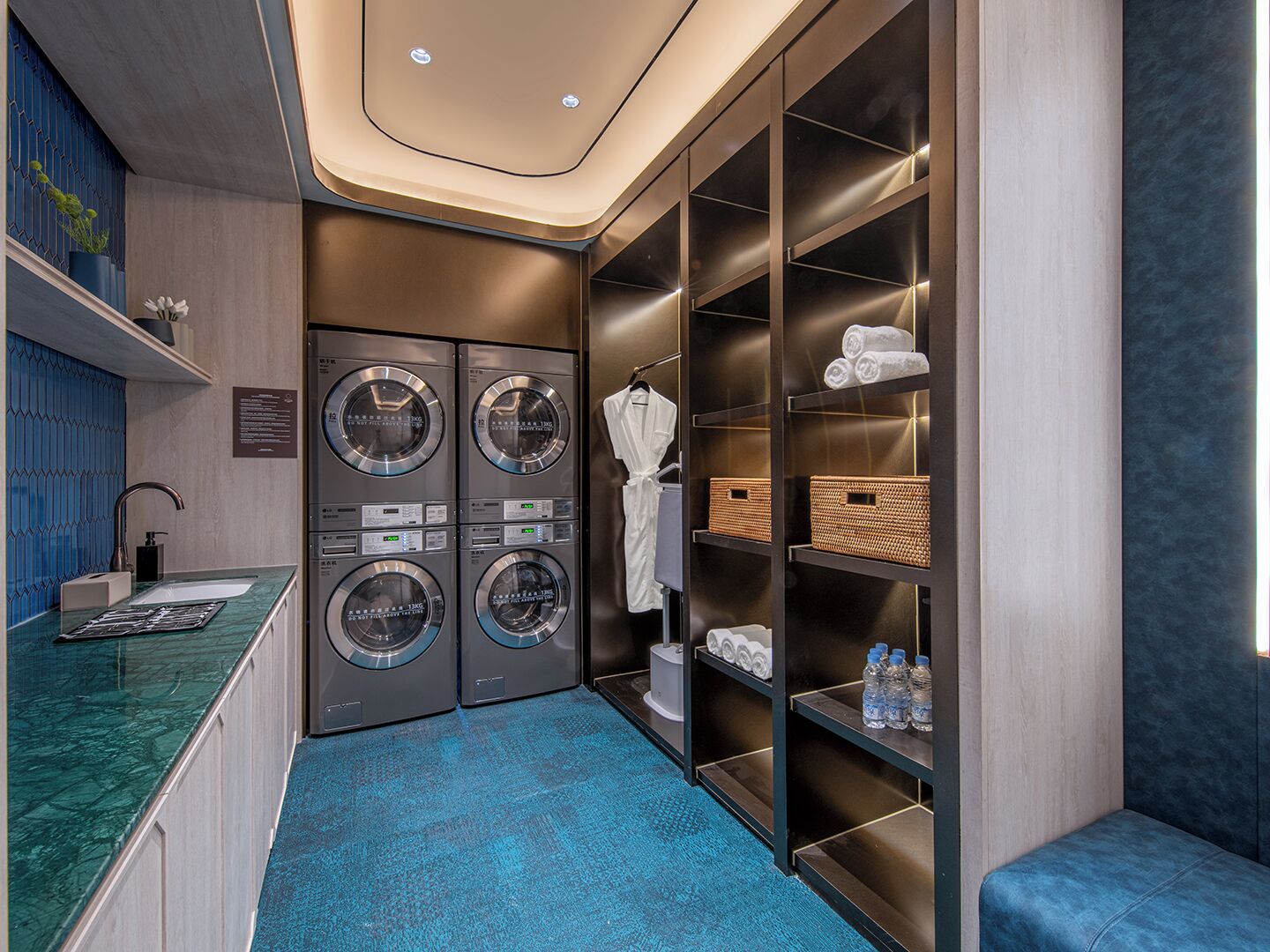 Une salle de bain d’hôtel moderne équipée de deux machines à laver, d’un lavabo et d’un porte-serviettes.