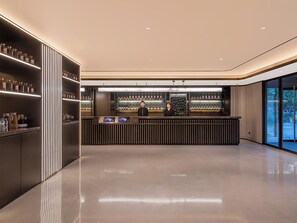 A modern bar area with a polished floor, a reception desk, and shelves stocked with bottles. - Crystal Hotel Beijing TianTan (Beijing)