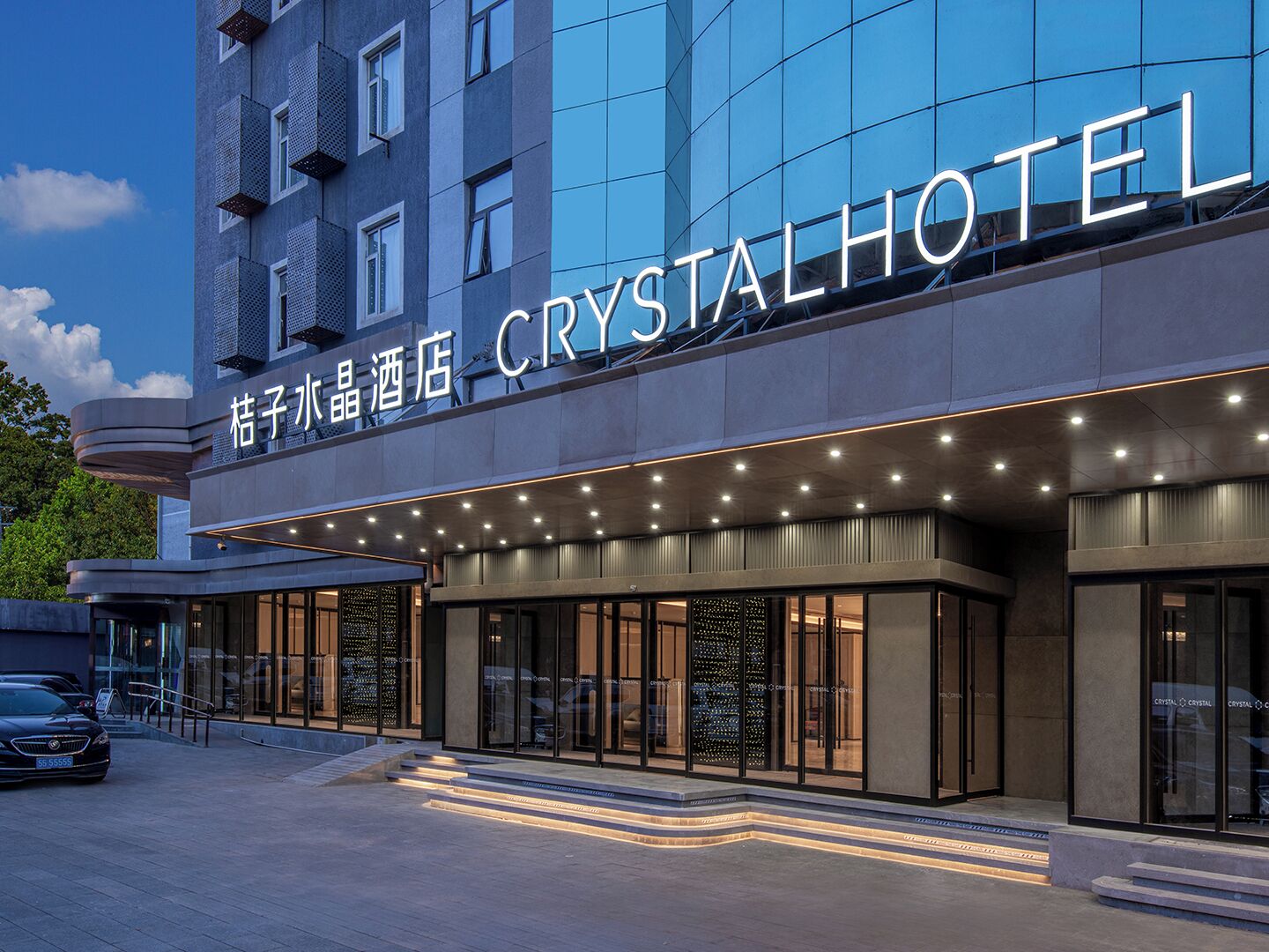 A hotel with a modern facade, large glass windows, and a prominent sign reading 'CRYSTAL HOTEL'.