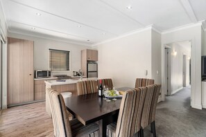 Eine moderne Küche mit Essbereich, ausgestattet mit einem Holztisch und gestreiften Stühlen, einer Mikrowelle und einem Kühlschrank.