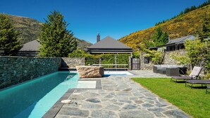 A swimming pool with stone tiles, a gazebo, and a stone wall. - Cardrona Haven - Resort spa & swimming pool! (Cardrona)