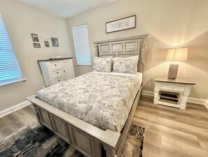 A bedroom with a bed, bedside tables, a nightstand, a lamp, and a wall-mounted sign. - 1 Block to Beach • Balcony • Family-Friendly- The heart of Myrtle Beach (Myrtle Beach)
