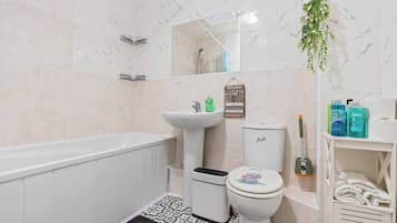A bathroom with a bathtub, sink, toilet, and a shower area.