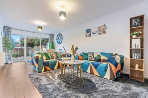 A modern living room with a sofa, a round coffee table, and a bookshelf. - #99 Quirky and Stylish 3-Bed Tamworth Centre Home (Staffordshire)
