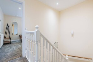 Eine Treppe mit weißen Balustraden und einer Handlauf, die zu einem Raum mit einem Spiegel und einer Leiter führt.