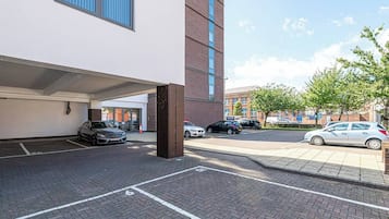 A parking area with cars, a building entrance, and a clear sky.