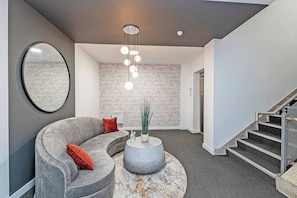 A modern interior with a curved grey sofa, a round coffee table, and a staircase. - #95 Crosby Gardens Apartment 2 beds & 1 bath (Waterloo)