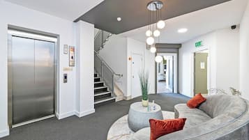 A modern lobby with a curved grey sofa, a round coffee table, and a staircase.