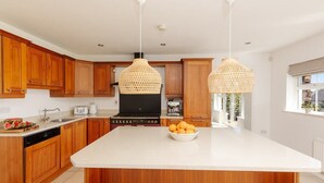 Uma cozinha moderna com armários de madeira, uma ilha central e duas luminárias pendentes.