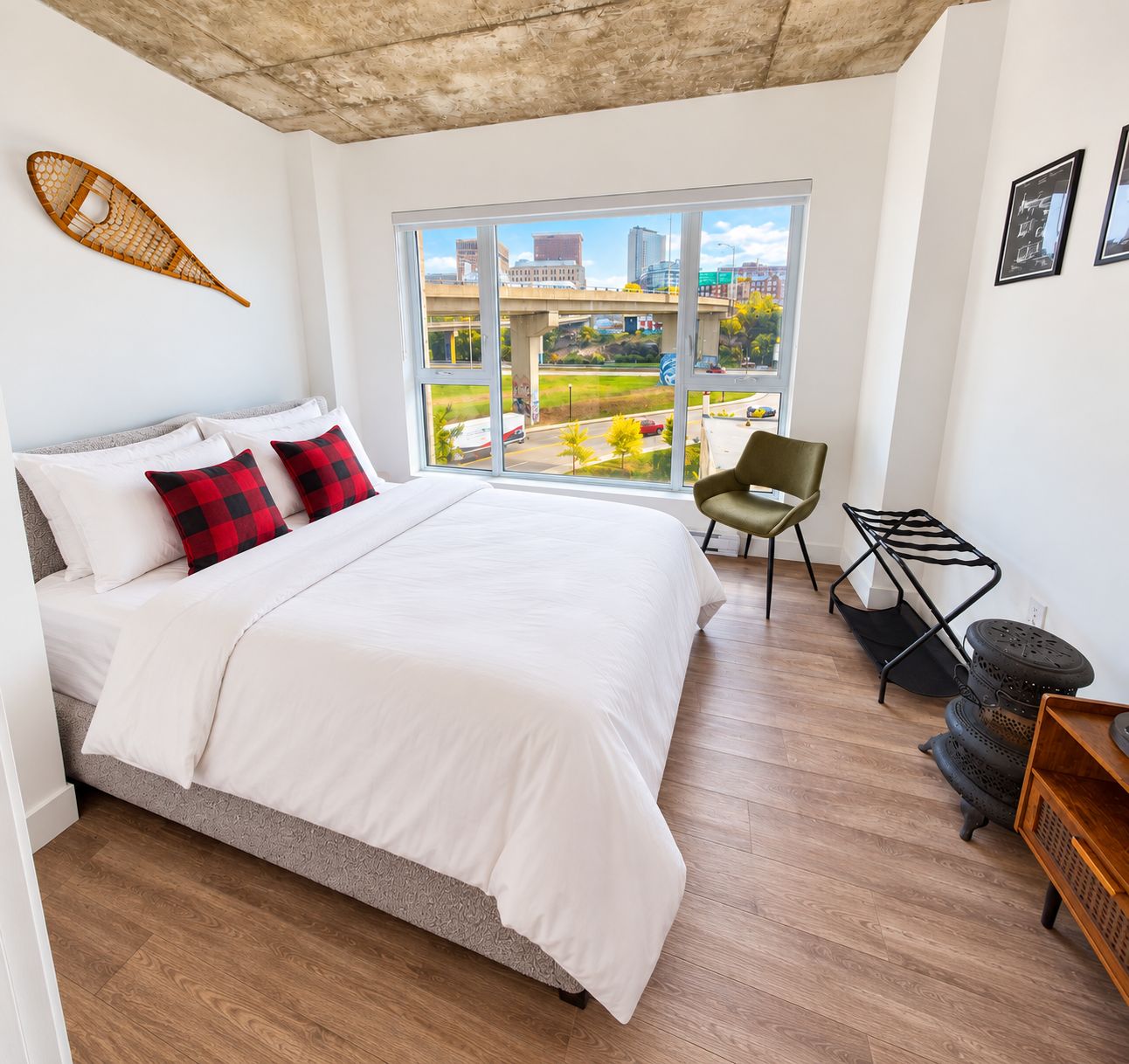 A bedroom with a large bed, a view of the city, and a chair.