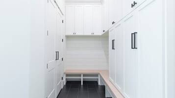 A narrow hallway with white cabinetry and a bench.