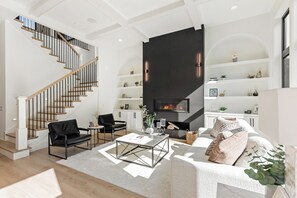 Una sala moderna con una escalera, una chimenea y una estantería.